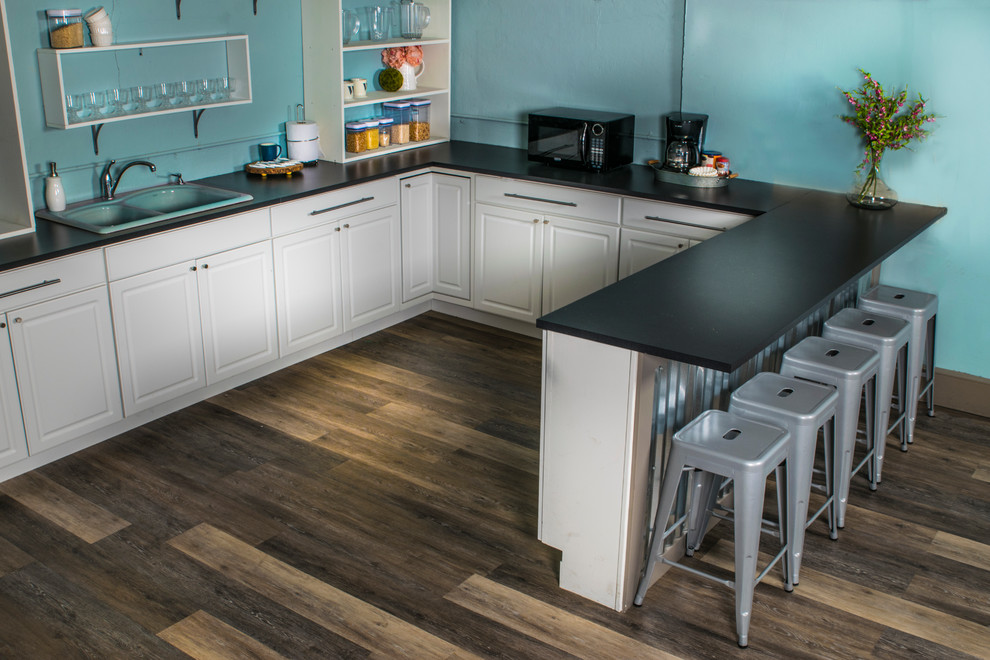 Mid-sized transitional u-shaped medium tone wood floor and beige floor enclosed kitchen photo in Indianapolis with a drop-in sink, open cabinets, white cabinets, quartz countertops, black appliances and a peninsula