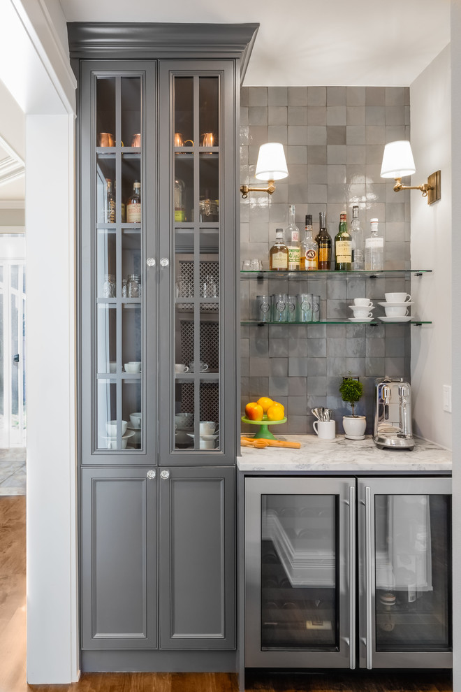 This is an example of a small eclectic single-wall wet bar in Seattle with recessed-panel cabinets, grey cabinets, quartzite benchtops, grey splashback, terra-cotta splashback, medium hardwood floors, brown floor and white benchtop.