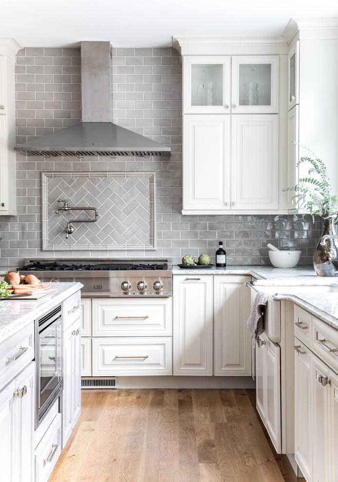 This is an example of a transitional l-shaped open plan kitchen in Boston with raised-panel cabinets, distressed cabinets, with island, a farmhouse sink, quartz benchtops and ceramic splashback.