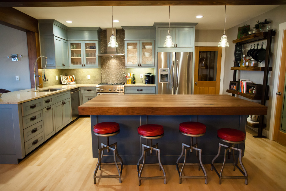Inspiration for a mid-sized country l-shaped open plan kitchen in Seattle with an undermount sink, shaker cabinets, blue cabinets, wood benchtops, grey splashback, stone tile splashback, stainless steel appliances, light hardwood floors and with island.