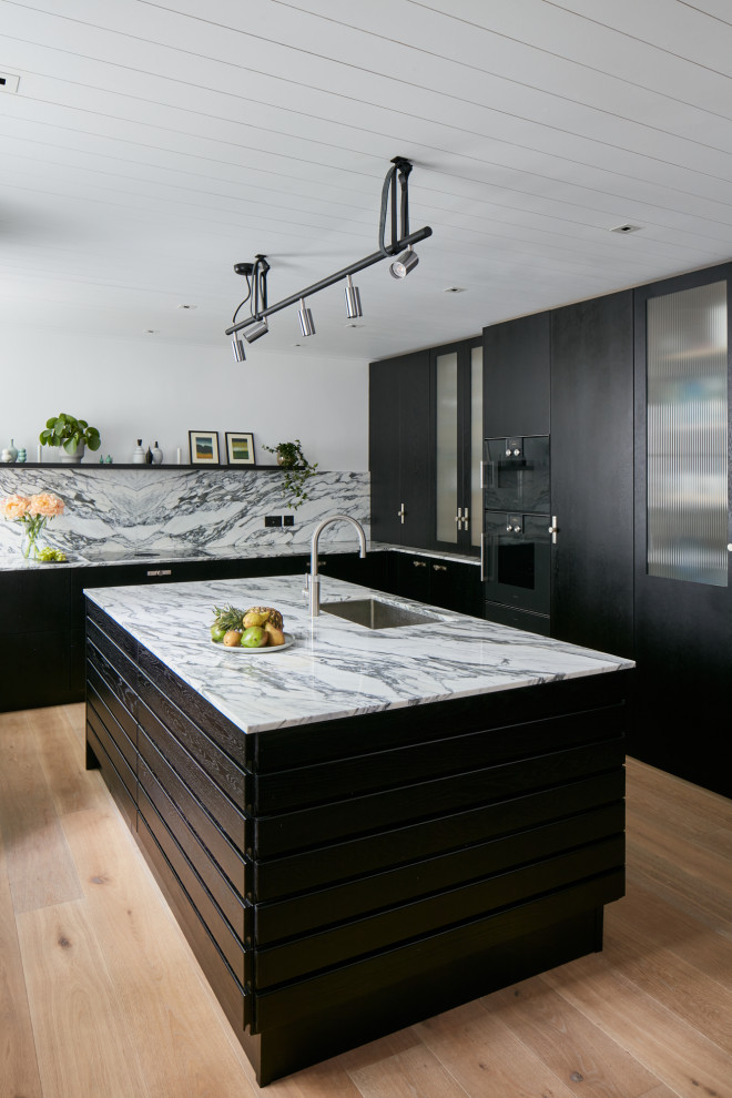 Large modern kitchen in London with flat-panel cabinets, black cabinets, marble benchtops, multi-coloured splashback, marble splashback, with island and white benchtop.