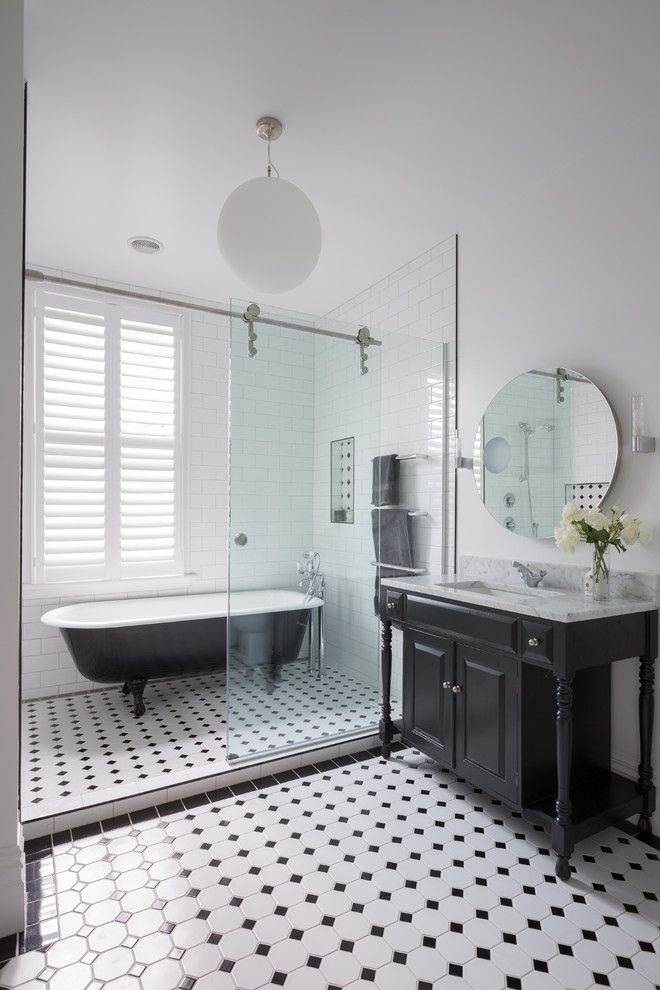 Traditional master bathroom in Auckland with black cabinets, a claw-foot tub, a shower/bathtub combo, glass tile, white walls, ceramic floors, an undermount sink and raised-panel cabinets.