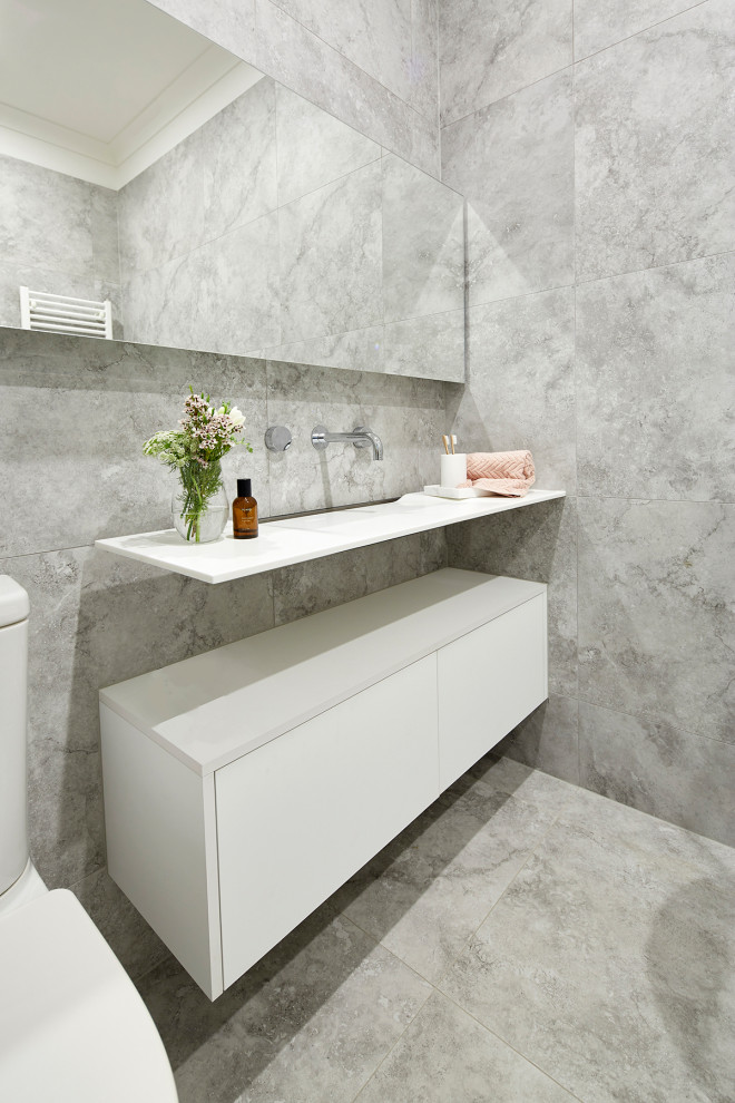 Design ideas for a small modern 3/4 bathroom in Melbourne with white cabinets, a freestanding tub, a corner shower, a wall-mount toilet, gray tile, stone tile, grey walls, marble floors, a console sink, laminate benchtops, grey floor, a hinged shower door, white benchtops and furniture-like cabinets.