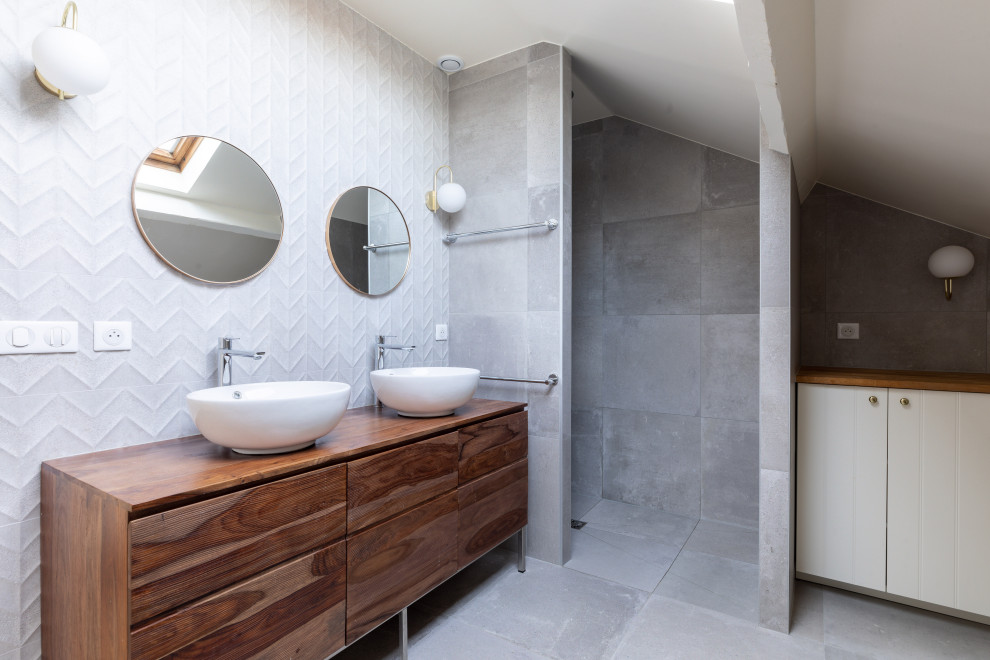 Design ideas for a mid-sized contemporary master bathroom in Paris with a curbless shower, gray tile, ceramic tile, grey walls, ceramic floors, a vessel sink, wood benchtops, grey floor, a double vanity, a freestanding vanity, flat-panel cabinets, medium wood cabinets, brown benchtops and vaulted.