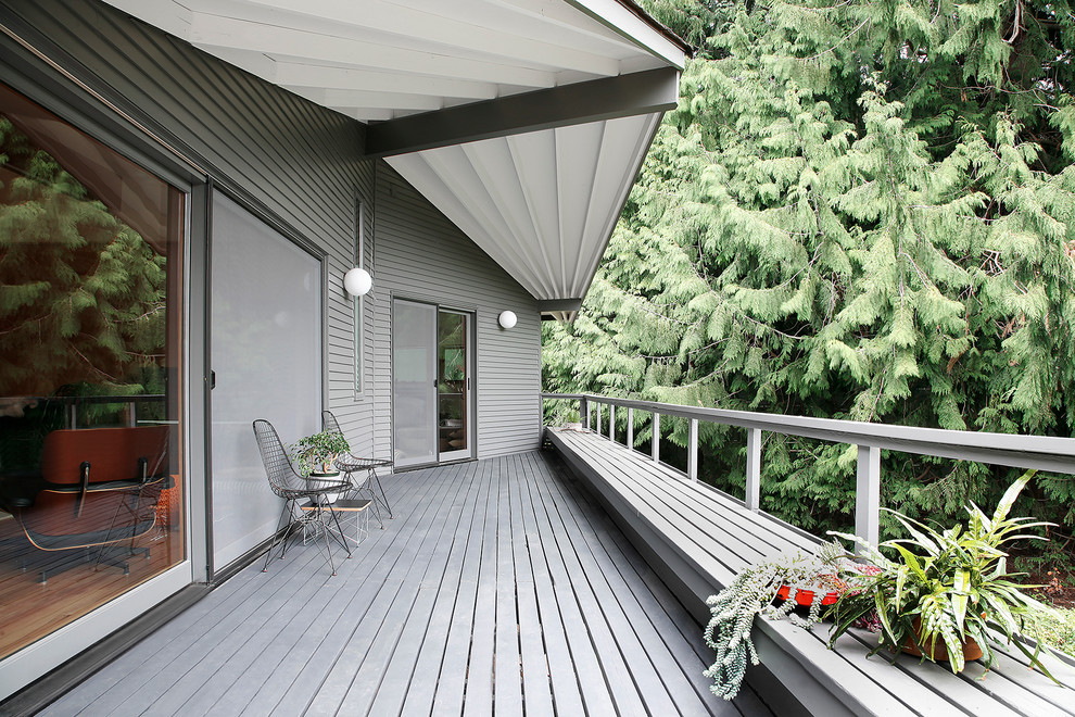 This is an example of a large midcentury backyard deck in Seattle with a roof extension.