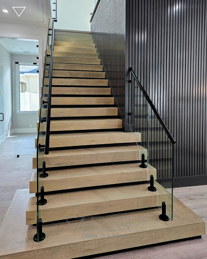 Large minimalist glass straight metal railing and wood wall staircase photo in Orlando