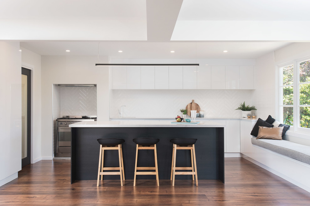 This is an example of a large contemporary kitchen in Other with an undermount sink, quartz benchtops, white splashback, ceramic splashback, stainless steel appliances, medium hardwood floors, with island, brown floor, white benchtop and flat-panel cabinets.
