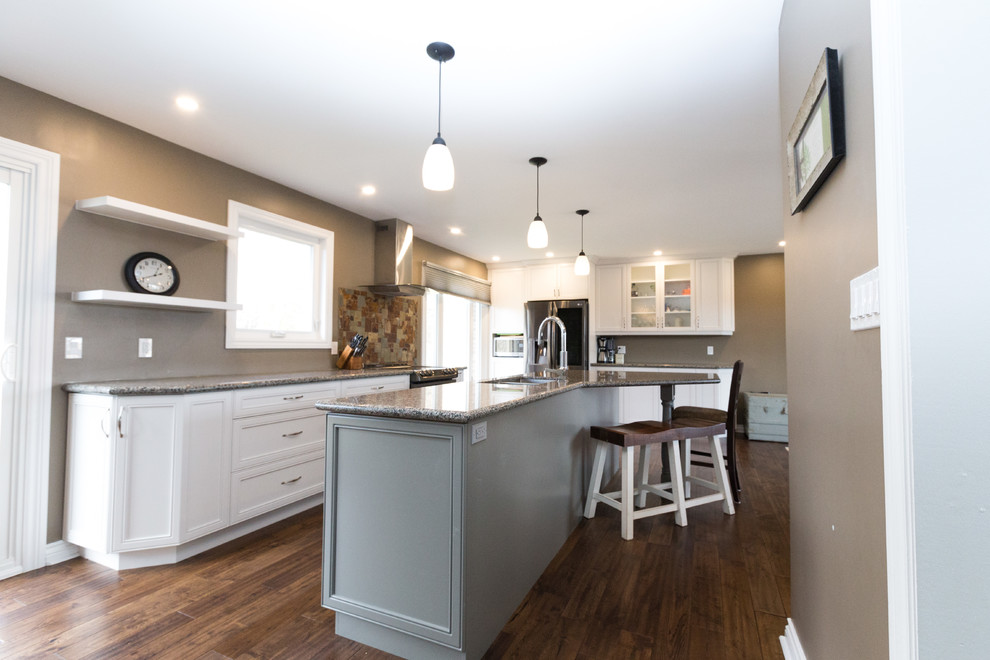 This is an example of a large traditional galley eat-in kitchen in Toronto with an undermount sink, recessed-panel cabinets, white cabinets, granite benchtops, multi-coloured splashback, slate splashback, stainless steel appliances, medium hardwood floors, with island and brown floor.
