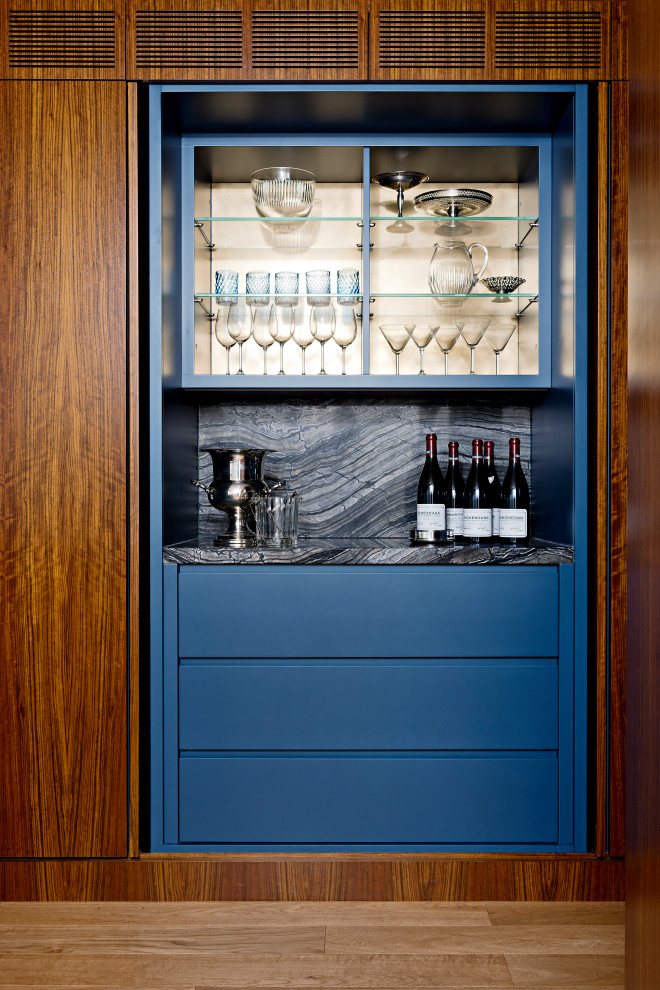 This is an example of a mid-sized contemporary single-wall home bar in Toronto with flat-panel cabinets, blue cabinets, granite benchtops, multi-coloured splashback, granite splashback, medium hardwood floors, brown floor and multi-coloured benchtop.