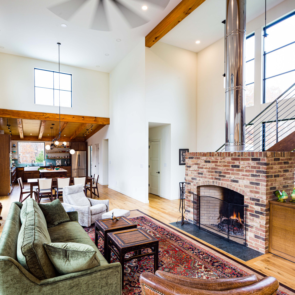 Inspiration for a small transitional open concept living room in Richmond with light hardwood floors, a standard fireplace, a brick fireplace surround and a concealed tv.