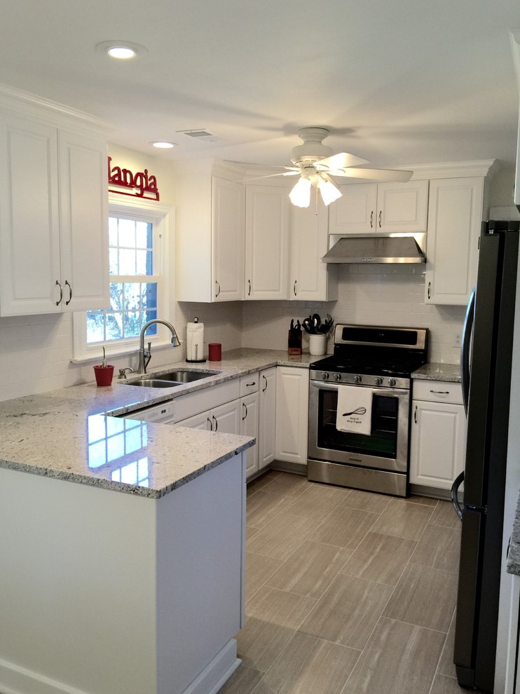 Example of a mid-sized transitional u-shaped porcelain tile enclosed kitchen design with an undermount sink, raised-panel cabinets, white cabinets, granite countertops, white backsplash, ceramic backsplash, stainless steel appliances and a peninsula