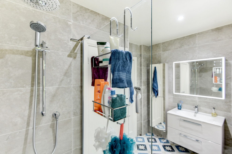 Kleines Modernes Badezimmer En Suite mit flächenbündigen Schrankfronten, beigen Schränken, offener Dusche, Wandtoilette mit Spülkasten, beigen Fliesen, Keramikfliesen, Keramikboden, Einbauwaschbecken, blauem Boden, offener Dusche, Einzelwaschbecken und schwebendem Waschtisch in Sussex