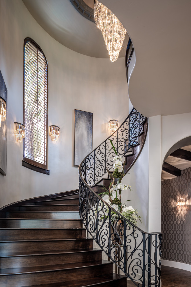 This is an example of an expansive transitional wood spiral staircase in Houston with metal railing.