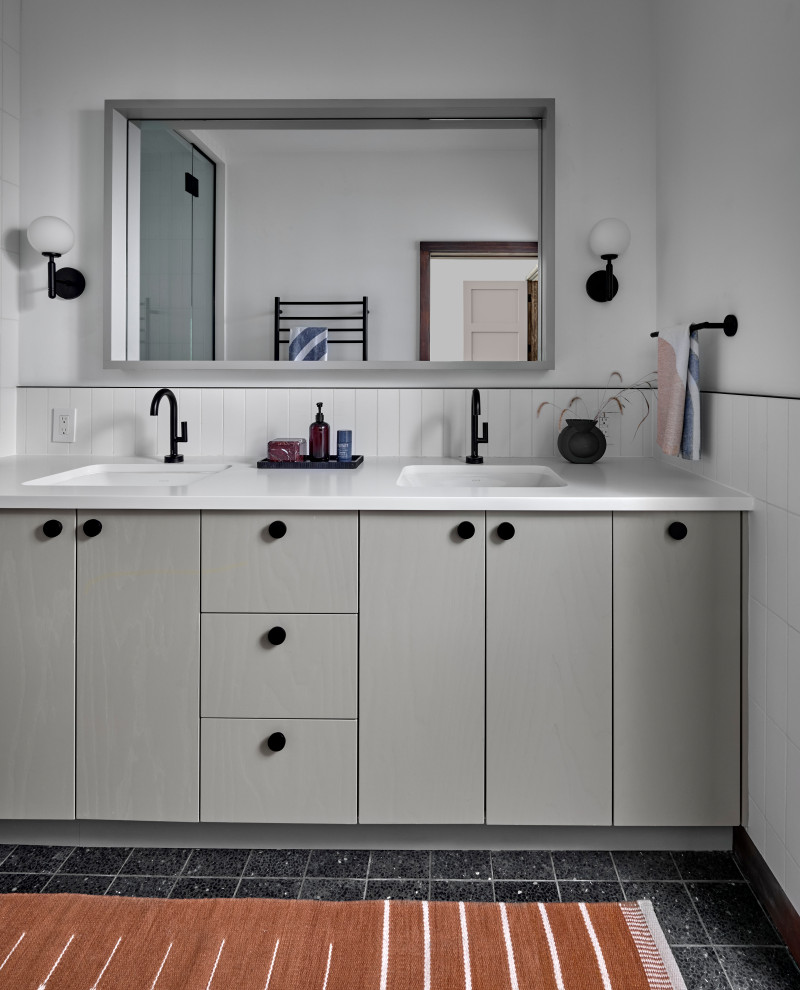 Photo of a mid-sized transitional master bathroom in Chicago with flat-panel cabinets, grey cabinets, a curbless shower, white tile, ceramic tile, white walls, terrazzo floors, an undermount sink, solid surface benchtops, black floor, a hinged shower door, white benchtops, an enclosed toilet, a double vanity and a built-in vanity.