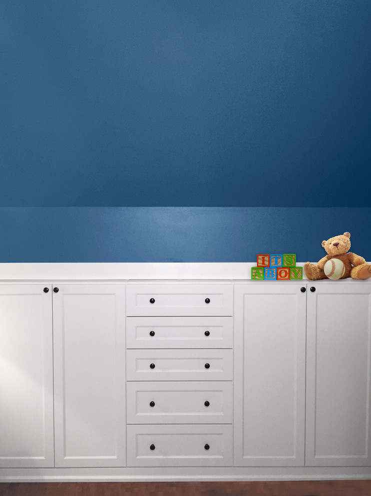 This is an example of a mid-sized transitional nursery for boys in Chicago with blue walls and dark hardwood floors.