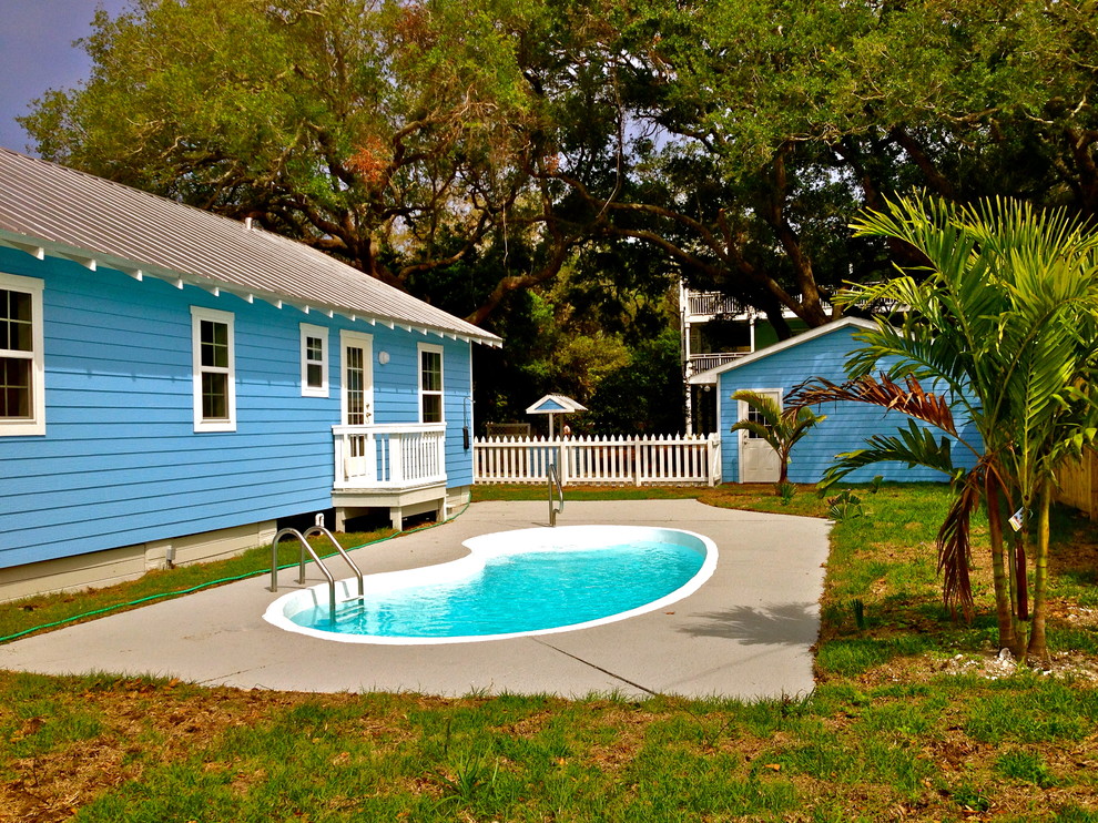 Photo of a small tropical backyard kidney-shaped lap pool in Jacksonville with concrete slab.
