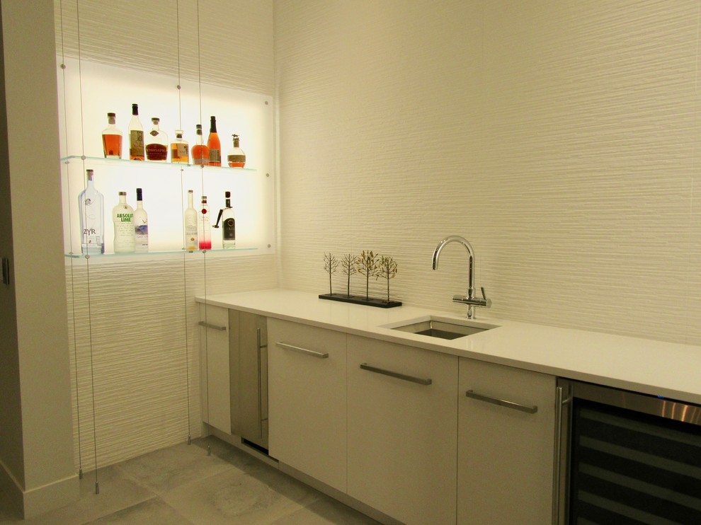 Photo of a mid-sized modern single-wall wet bar in San Francisco with an undermount sink, flat-panel cabinets, white cabinets, quartz benchtops, white splashback, porcelain splashback, porcelain floors and grey floor.