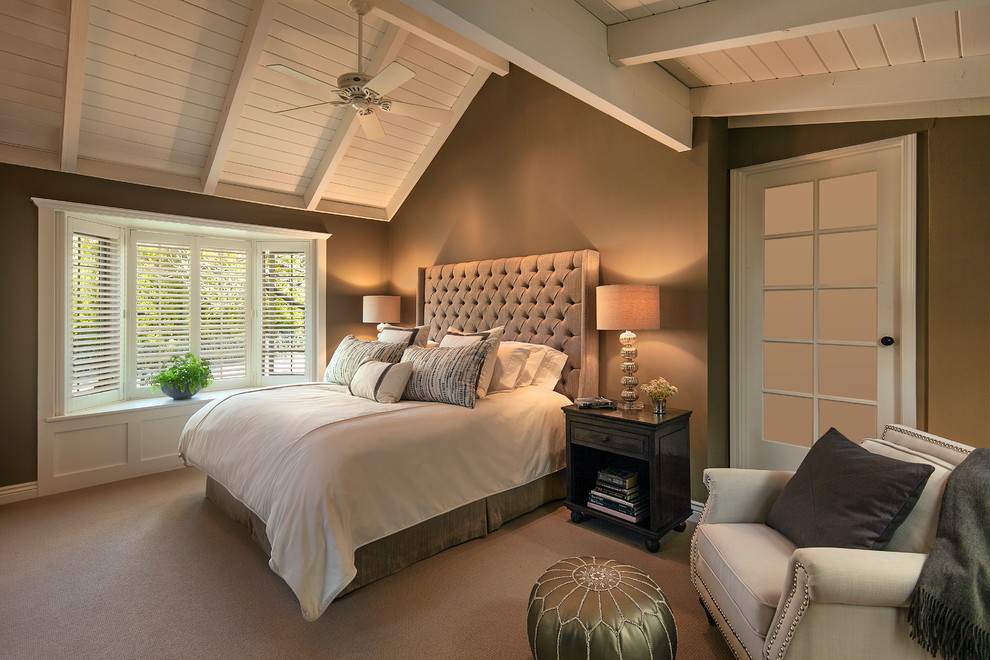This is an example of a large transitional master bedroom in Santa Barbara with brown walls and carpet.