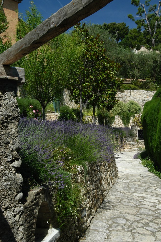 Mediterranean sloped full sun garden in Nice with natural stone pavers.