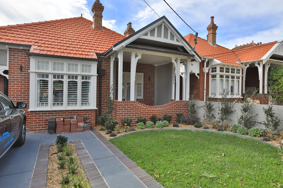 This is an example of a large modern one-storey brick brown house exterior in Sydney with a gable roof and a tile roof.