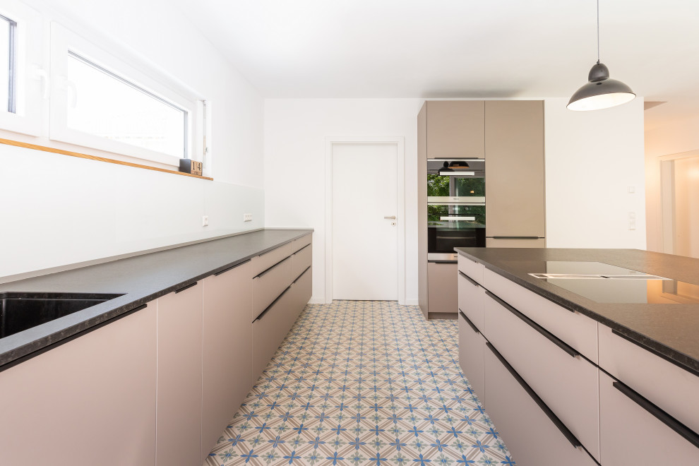Design ideas for a contemporary l-shaped open plan kitchen in Frankfurt with a single-bowl sink, beaded inset cabinets, beige cabinets, white splashback, glass sheet splashback, terra-cotta floors, with island and multi-coloured floor.