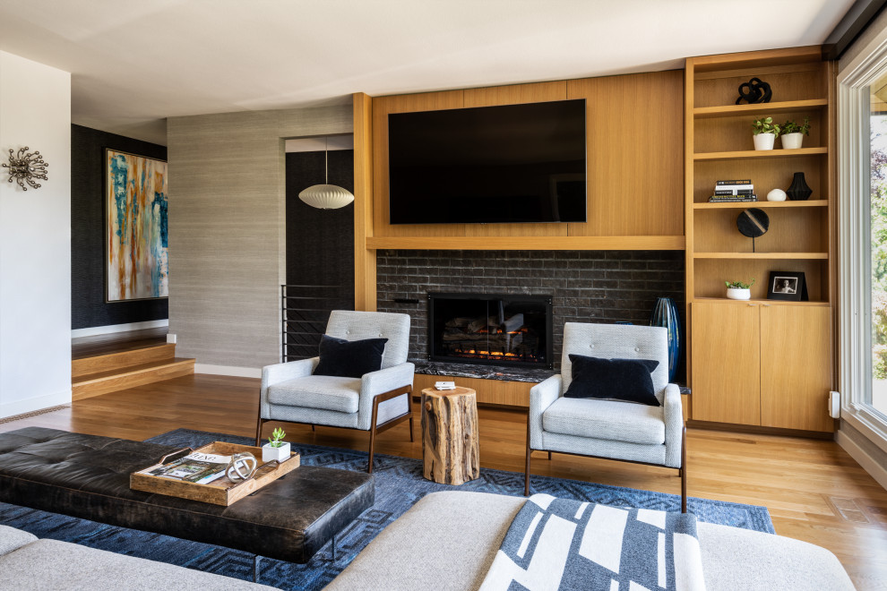 Design ideas for a mid-sized contemporary enclosed family room in Seattle with grey walls, medium hardwood floors, a standard fireplace, a brick fireplace surround, a wall-mounted tv and wallpaper.