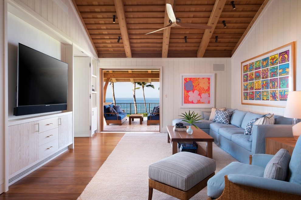 Design ideas for a large tropical open concept family room in Hawaii with white walls, medium hardwood floors, no fireplace, a wall-mounted tv and brown floor.