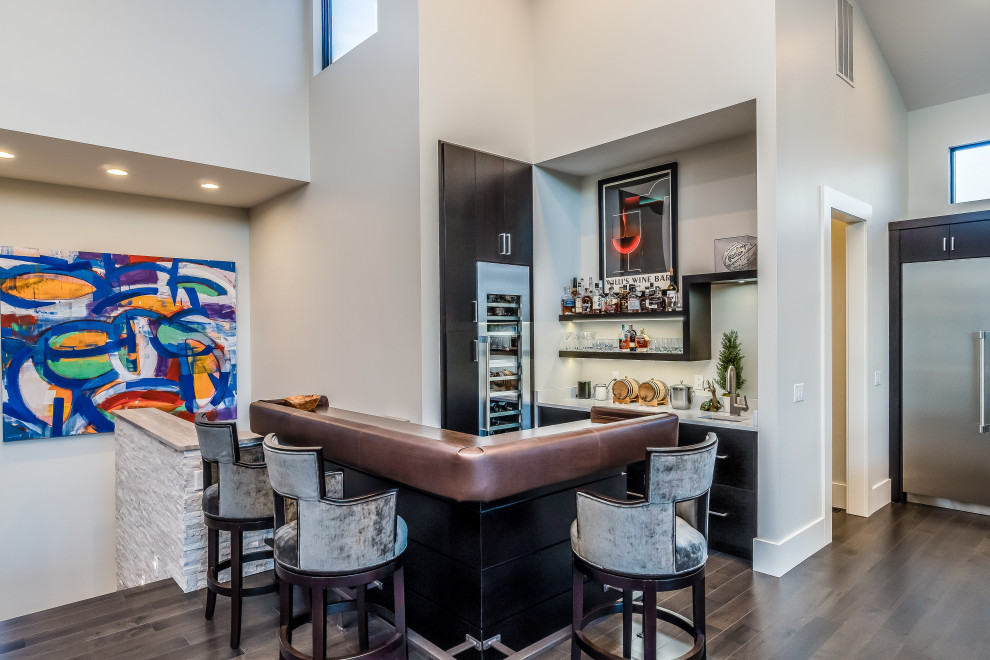 Design ideas for a contemporary l-shaped home bar in Other with an undermount sink, flat-panel cabinets, black cabinets, dark hardwood floors, brown floor and white benchtop.