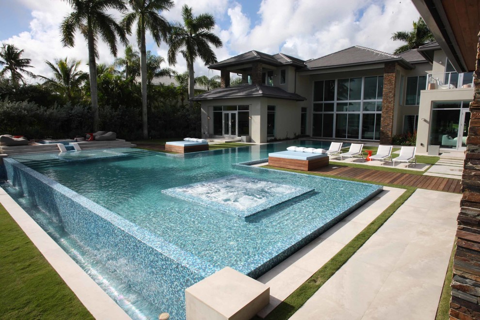 Inspiration for a large contemporary backyard custom-shaped pool in Miami with a water feature and concrete pavers.