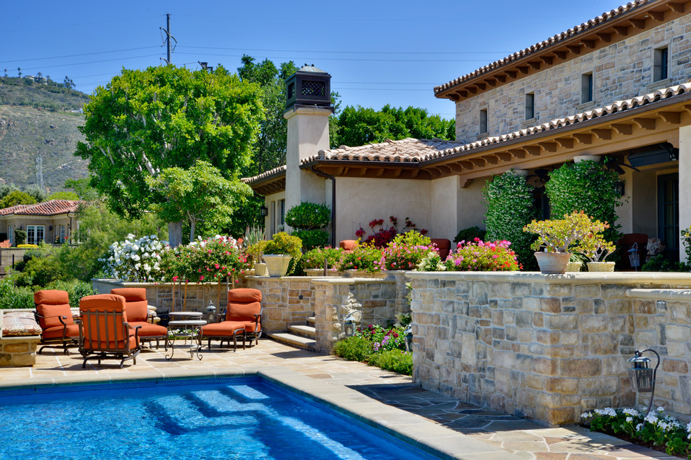 Photo of a large mediterranean backyard rectangular lap pool in San Diego with natural stone pavers.