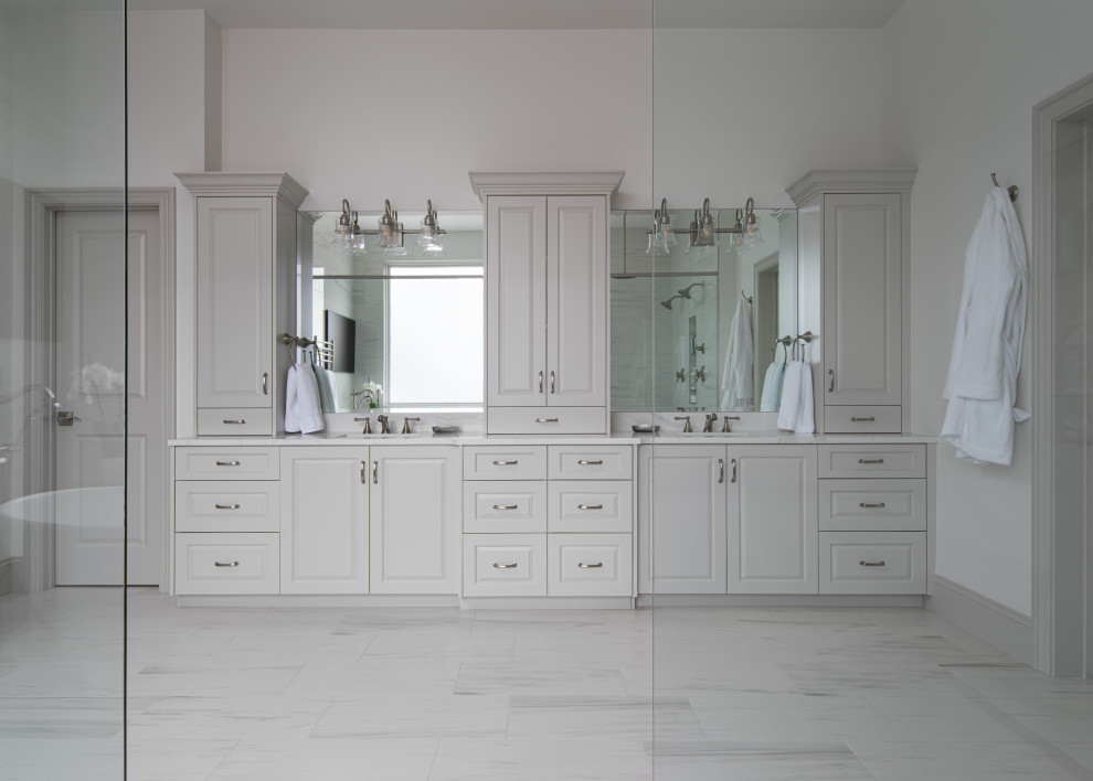 Photo of a large transitional master bathroom with raised-panel cabinets, grey cabinets, porcelain floors, engineered quartz benchtops, grey floor, white benchtops, an enclosed toilet, a double vanity and a built-in vanity.