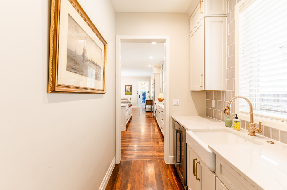 Large transitional l-shaped dark wood floor and brown floor open concept kitchen photo in Denver with a farmhouse sink, shaker cabinets, beige cabinets, quartz countertops, beige backsplash, ceramic backsplash, stainless steel appliances, an island and white countertops