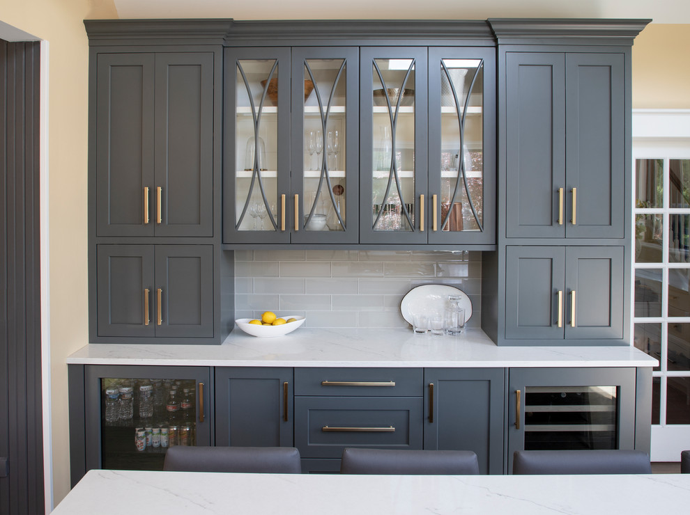 Example of a large transitional u-shaped medium tone wood floor kitchen design with an undermount sink, gray cabinets, quartz countertops, gray backsplash, glass tile backsplash, stainless steel appliances, an island and white countertops