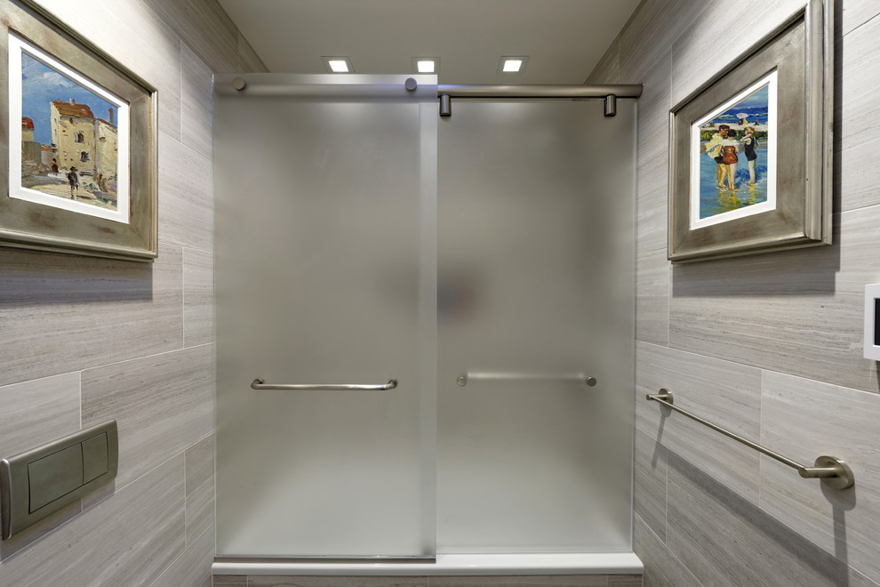 Mid-sized contemporary kids bathroom in DC Metro with furniture-like cabinets, medium wood cabinets, an alcove tub, a shower/bathtub combo, a wall-mount toilet, gray tile, marble, grey walls, slate floors, a vessel sink, limestone benchtops, grey floor, a sliding shower screen and grey benchtops.