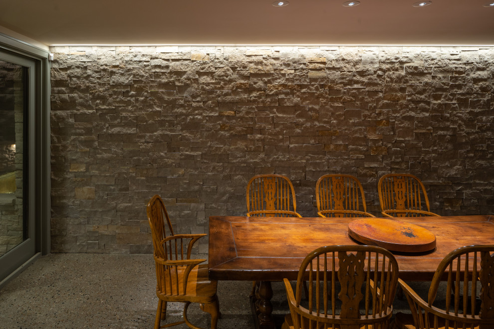 Immagine di una sala da pranzo aperta verso la cucina rustica con pareti gialle e pavimento in cemento