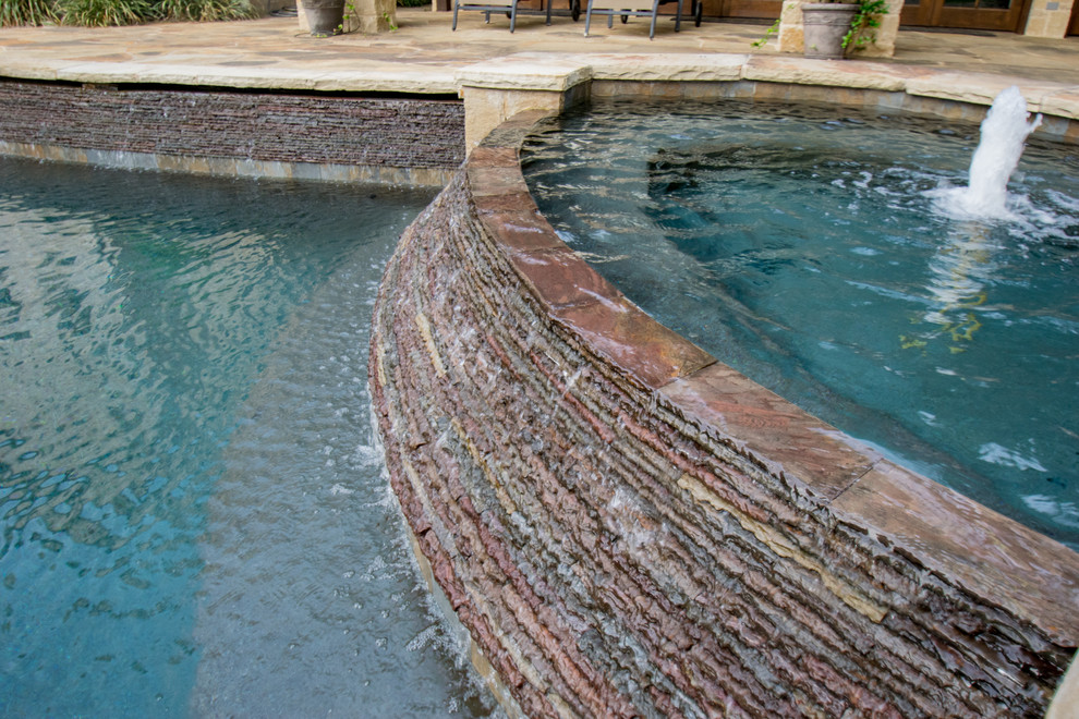 Design ideas for a mid-sized country backyard custom-shaped pool in Dallas with a water feature and natural stone pavers.