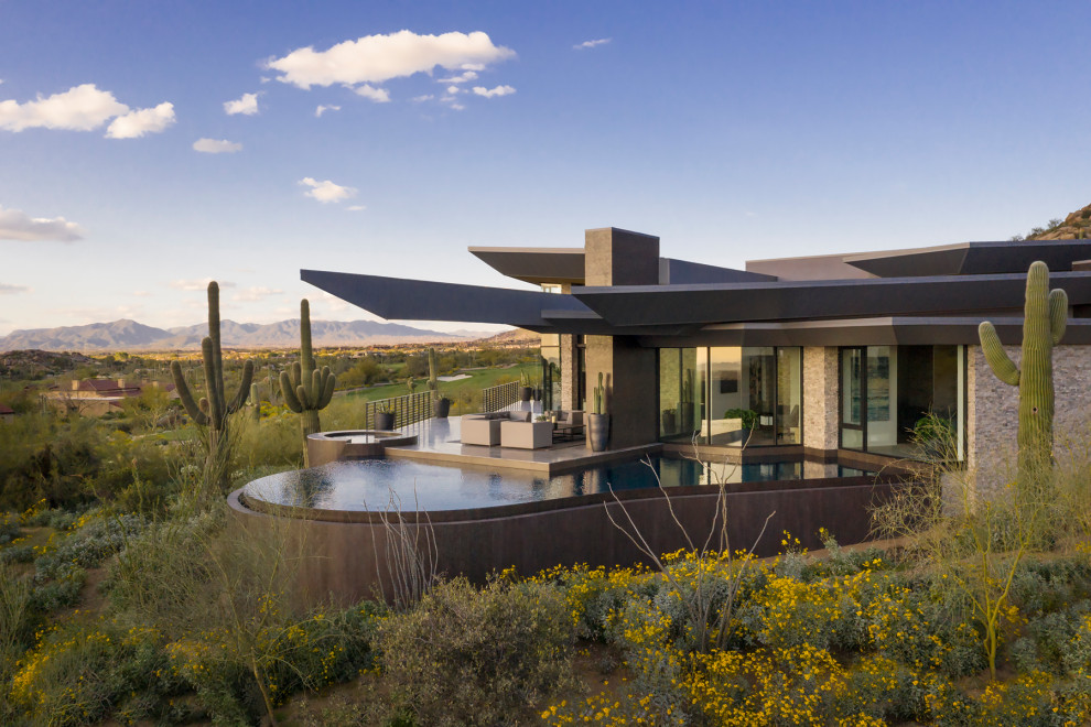 This is an example of a large modern custom-shaped infinity pool in Phoenix with a hot tub.