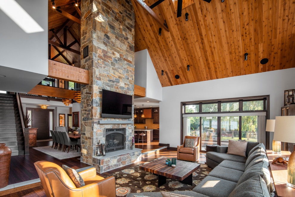 Photo of a country open concept family room in Chicago with white walls, dark hardwood floors, a standard fireplace, a stone fireplace surround, a wall-mounted tv, vaulted and wood.