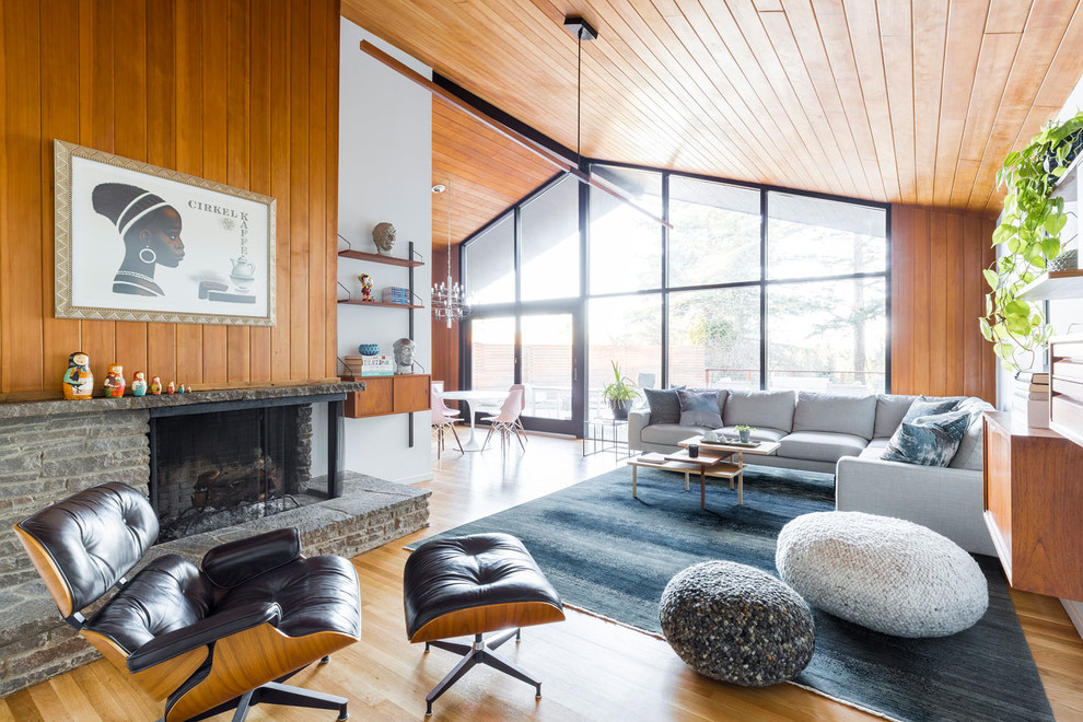 Design ideas for a large midcentury open concept living room in Portland with white walls, light hardwood floors, a standard fireplace, a stone fireplace surround, no tv and beige floor.