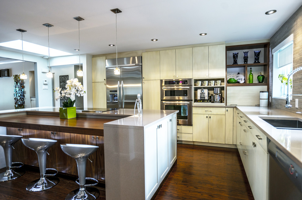Example of a trendy l-shaped eat-in kitchen design in Montreal with an undermount sink, flat-panel cabinets, distressed cabinets, quartz countertops, gray backsplash, porcelain backsplash and stainless steel appliances