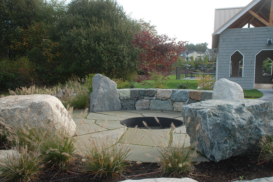 Photo of a mid-sized craftsman backyard stone landscaping in Seattle with a fire pit.