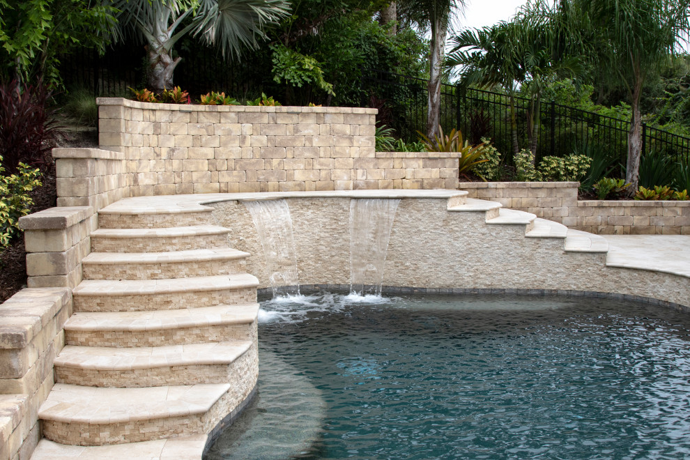 Inspiration for a tropical backyard custom-shaped pool in Orlando with with a pool and natural stone pavers.