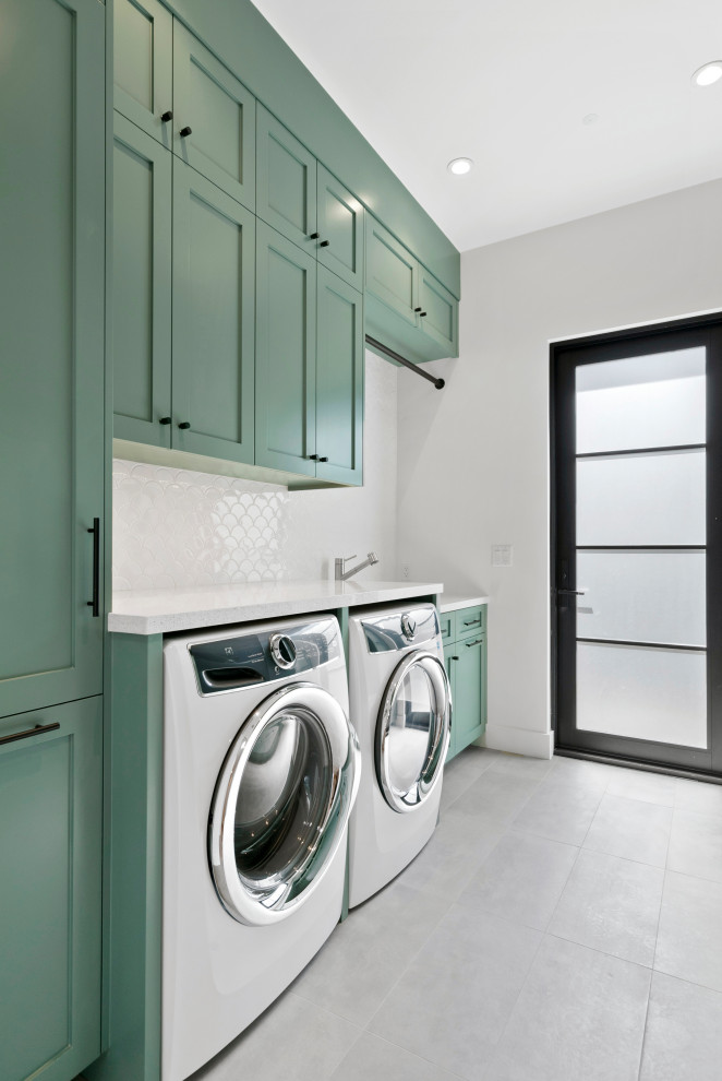 Mid-sized country single-wall utility room in San Francisco with shaker cabinets, green cabinets, grey walls, concrete floors, a side-by-side washer and dryer and grey floor.