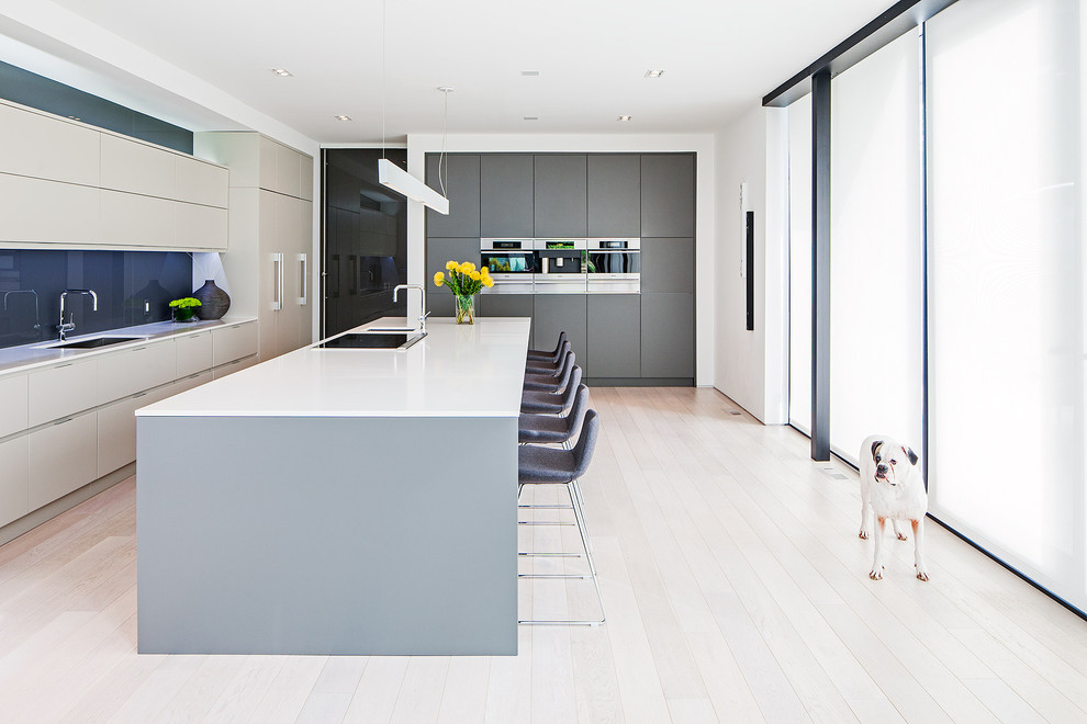 This is an example of a scandinavian galley kitchen in Toronto with an undermount sink, flat-panel cabinets, grey cabinets, blue splashback and glass sheet splashback.