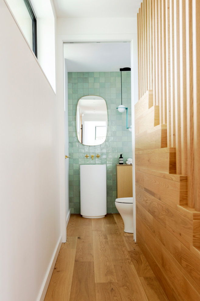 Idéer för funkis brunt toaletter, med vita skåp, en toalettstol med separat cisternkåpa, grön kakel, keramikplattor, mellanmörkt trägolv, ett piedestal handfat, träbänkskiva och brunt golv