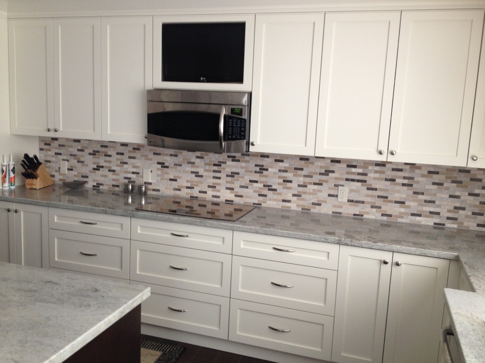 Kitchen - large transitional l-shaped dark wood floor and brown floor kitchen idea in Miami with an island, a double-bowl sink, shaker cabinets, white cabinets, quartzite countertops, multicolored backsplash, glass tile backsplash and stainless steel appliances