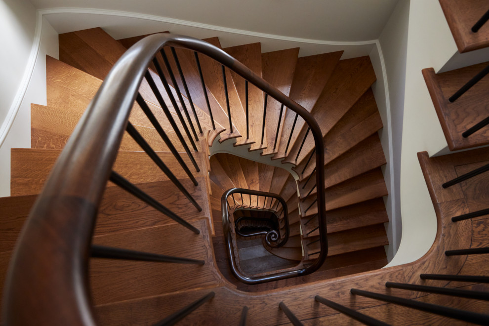 Свежая идея для дизайна: изогнутая лестница среднего размера в классическом стиле с деревянными ступенями, крашенными деревянными подступенками и металлическими перилами - отличное фото интерьера