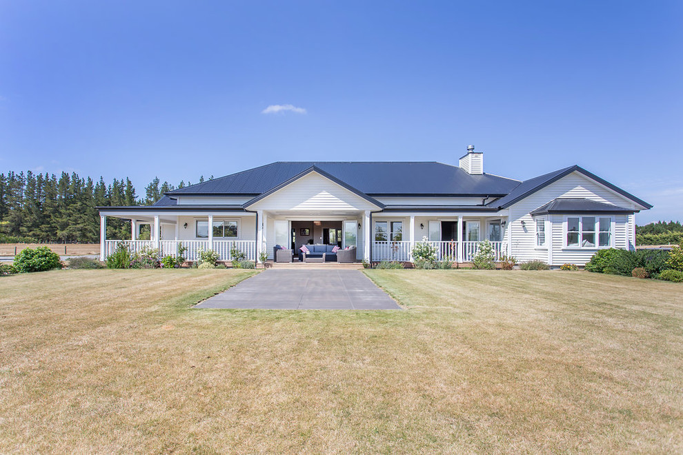 This is an example of an Expansive country One-storey White house exterior in Christchurch With Mixed Siding, a Hip Roof and a Mixed Roof.