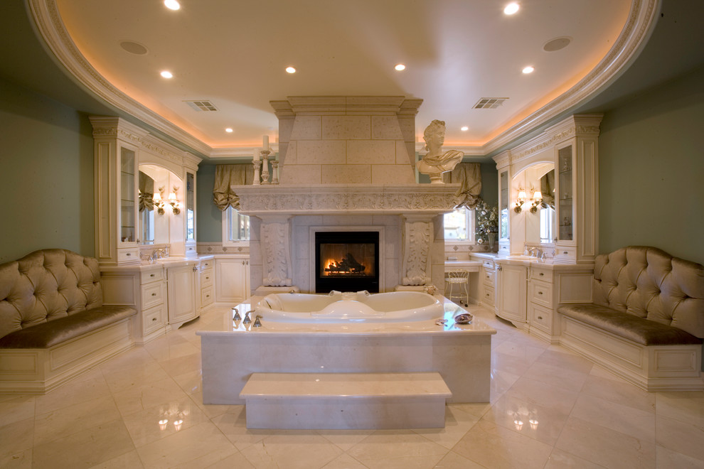 Large mediterranean master bathroom in Las Vegas with a drop-in tub, beige tile, raised-panel cabinets, white cabinets, green walls, marble floors and white floor.