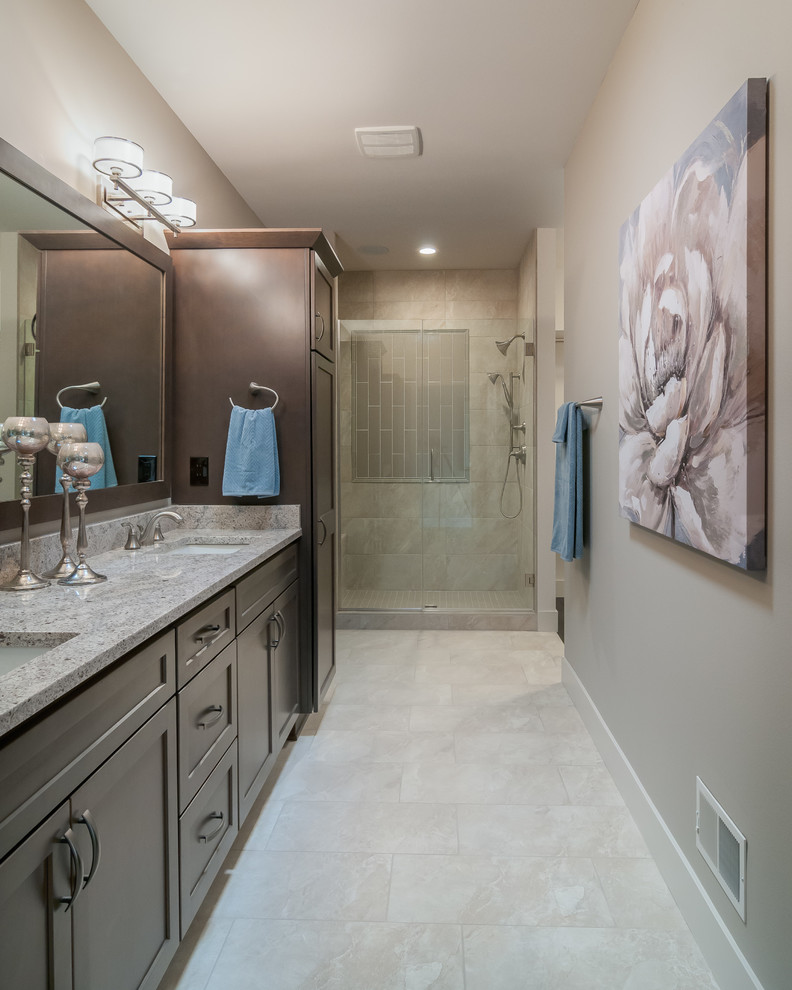 Photo of a mid-sized transitional master bathroom in Milwaukee with recessed-panel cabinets, brown cabinets, a corner shower, grey walls, ceramic floors, an undermount sink, granite benchtops, white floor and a hinged shower door.